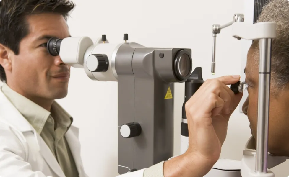 An eye doctor performing an eye exam on a patient using a slit lamp.